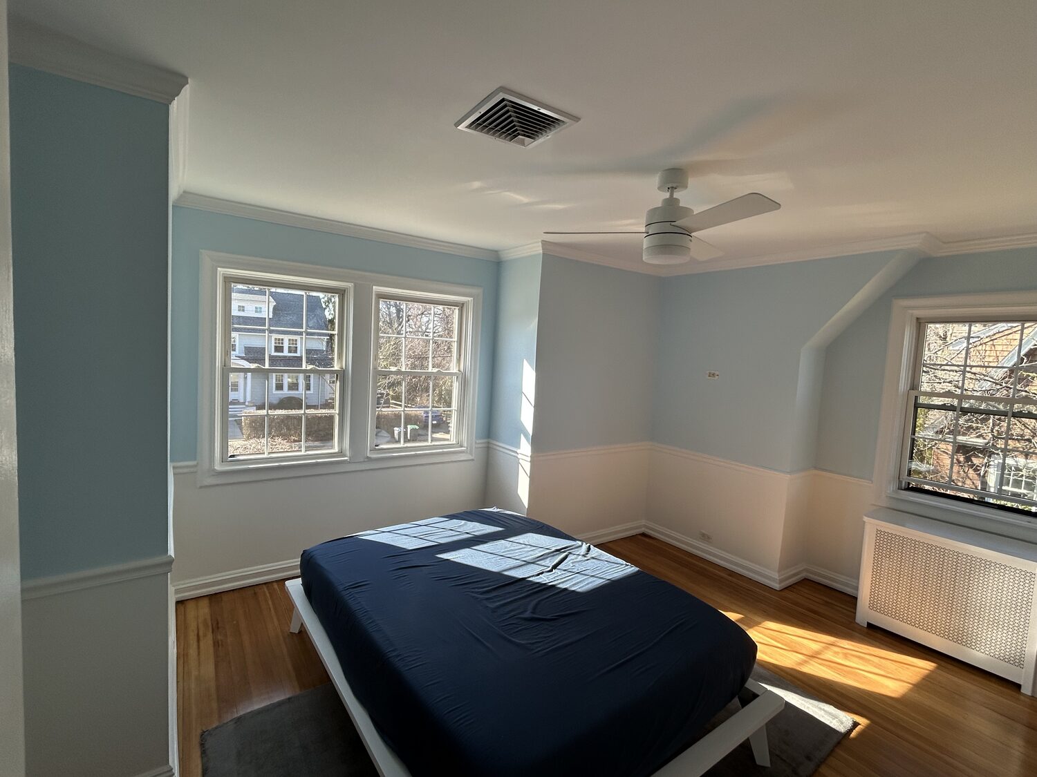 Finished soft blue bedroom with white wainscoting