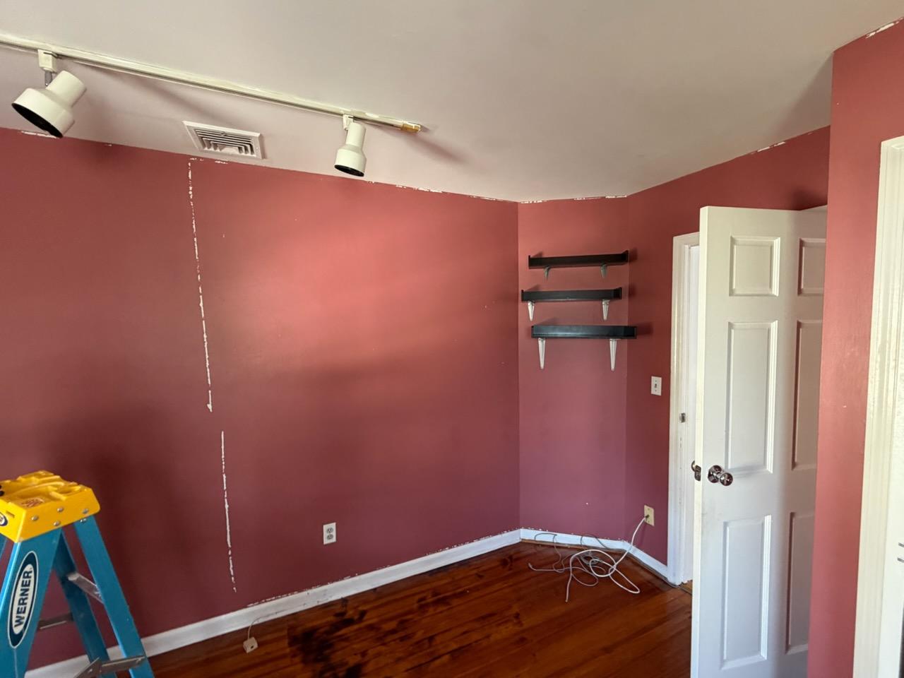 Bedroom in deep rose with patched wall repairs before repainting