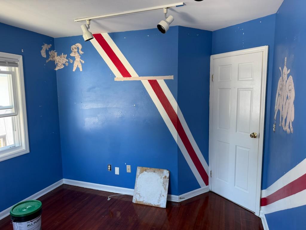 Children's bedroom painted blue with a red and white diagonal stripe and cartoon wall decals before repainting