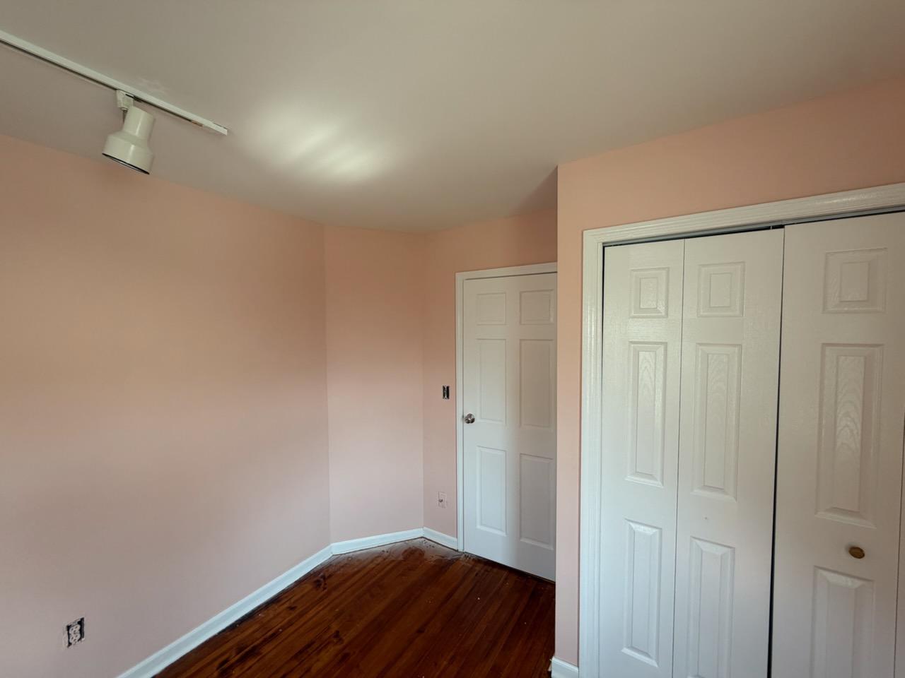The same bedroom repainted soft peach with white trim and closet doors